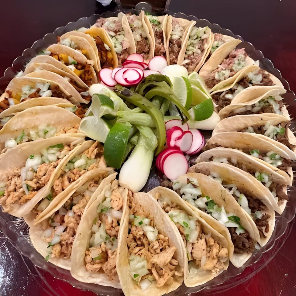 A large platter of Silantro Lime Tacos, featuring various meats, onions, cilantro, radishes, and lime wedges.