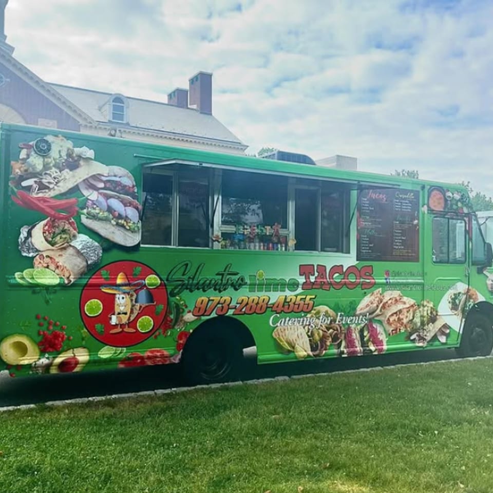Silantro Lime Tacos food truck, green with vibrant Mexican food and logo, parked on grass.